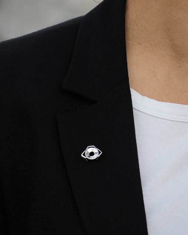 Pin Calak mate plateado en solapa de saco negro