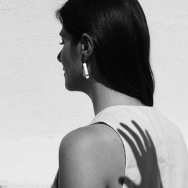 Pendientes triangulares plateados con veteado gris, llevados en la oreja