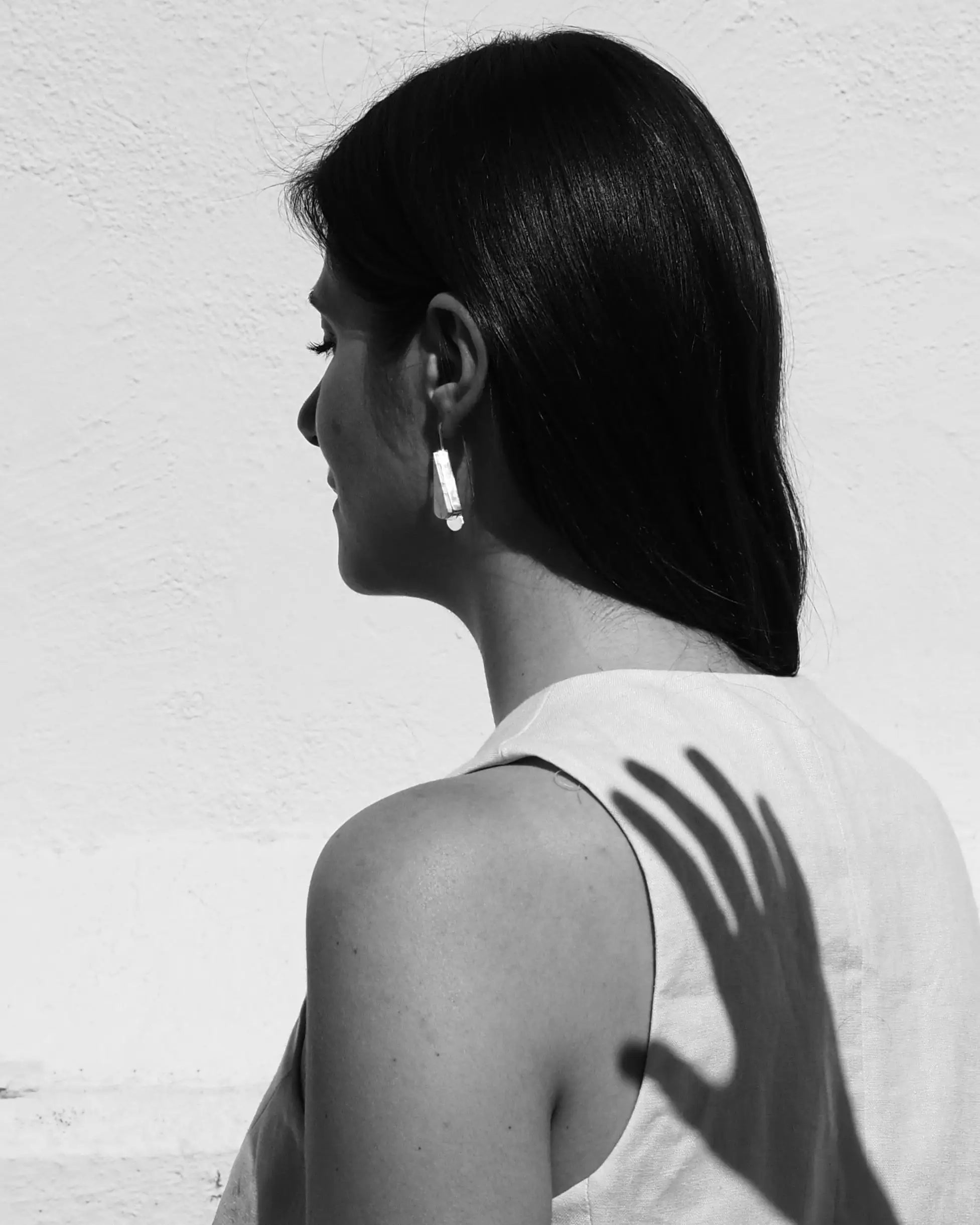 Pendientes triangulares plateados con veteado gris, llevados en la oreja