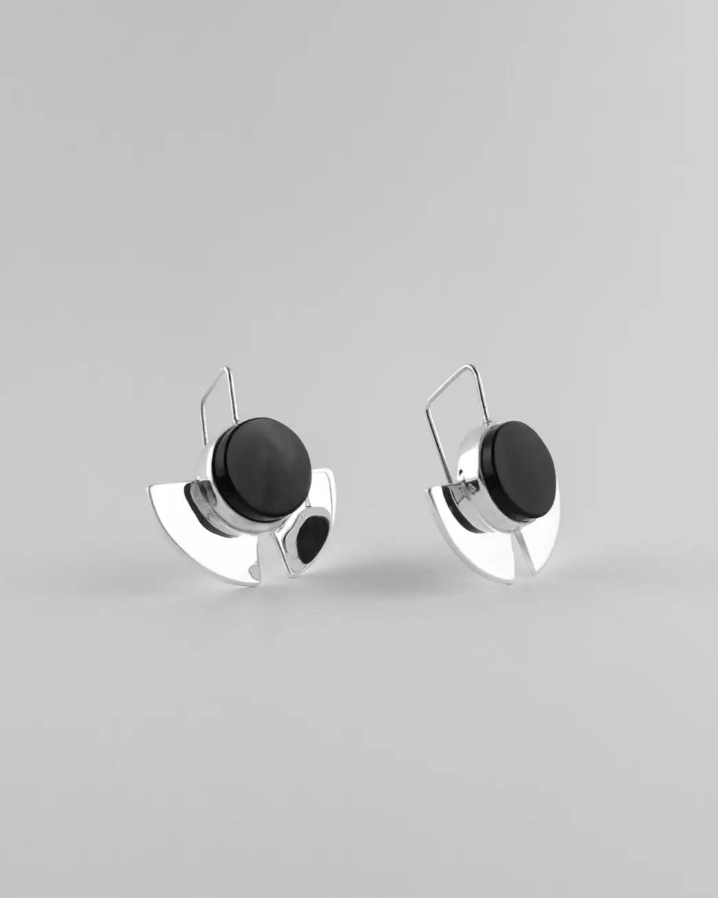 Pendientes con disco negro y base plateada tipo soporte, vista frontal