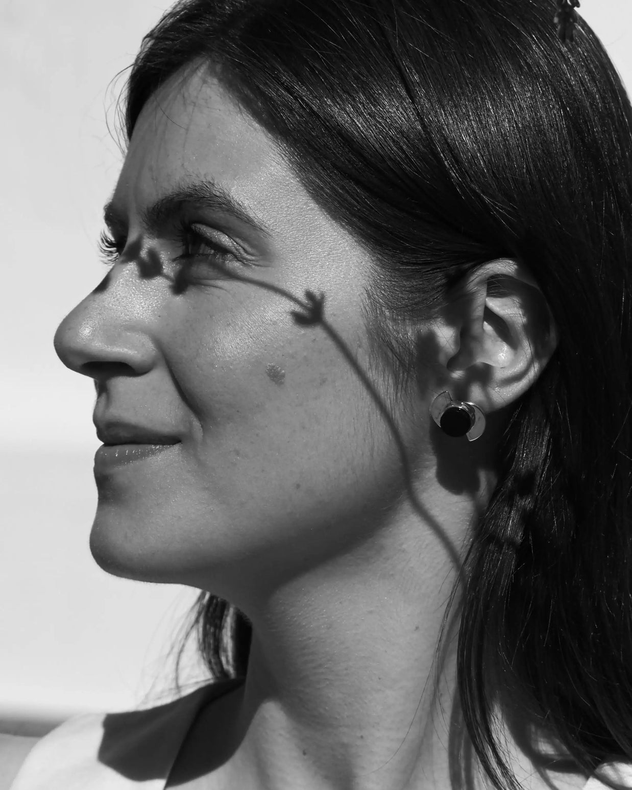 Pendientes elípticos negros con montura plateada, oreja de perfil