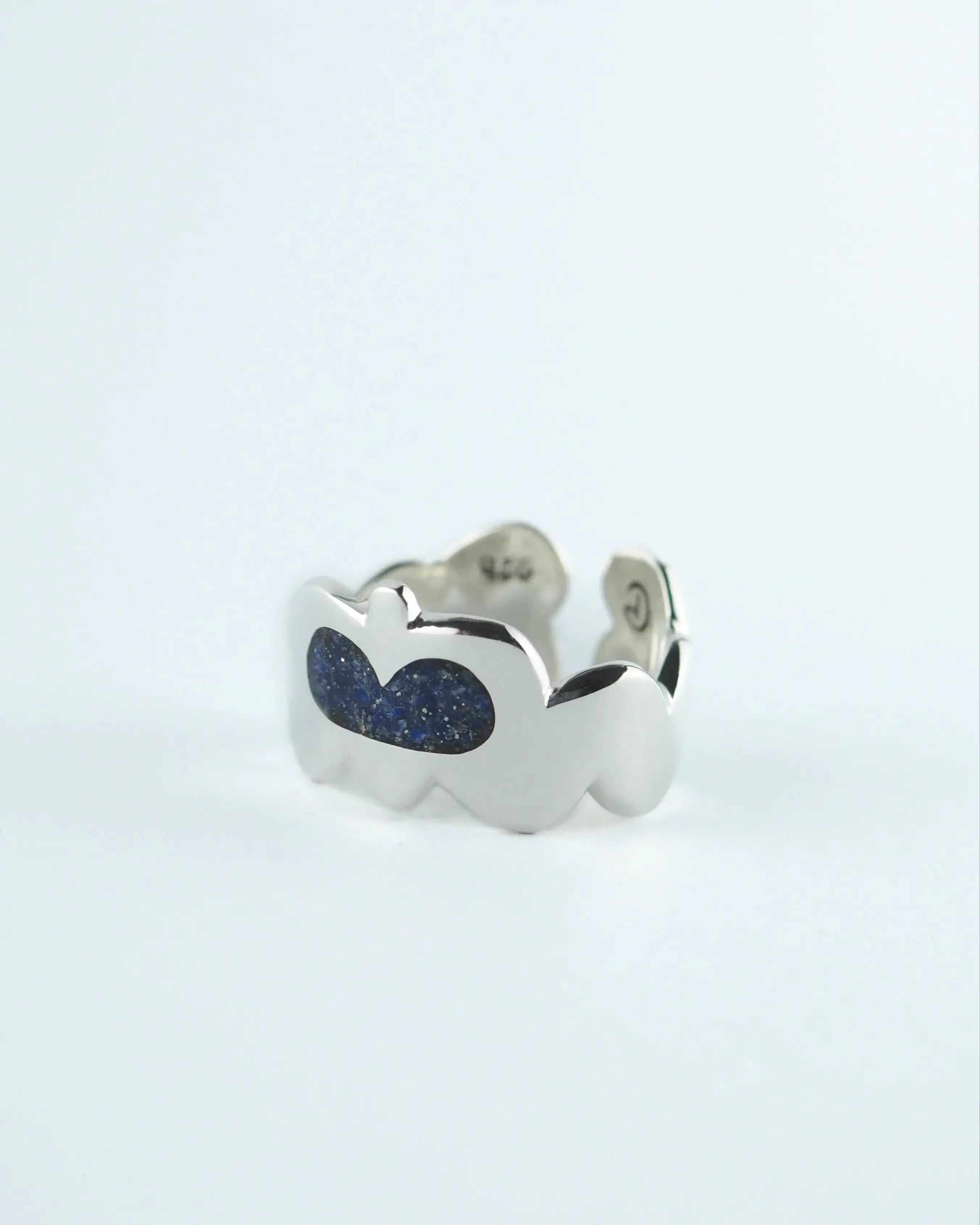 Anillo plateado con dos piedras ovaladas azules y detalle en el lateral
