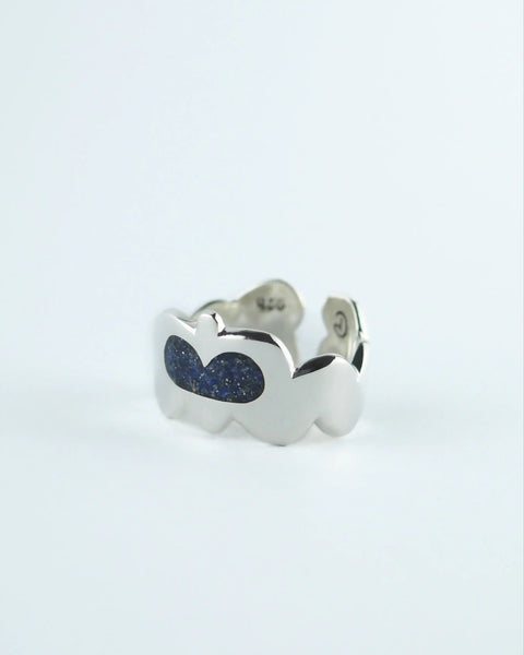 Anillo plateado con dos piedras ovaladas azules y detalle en el lateral