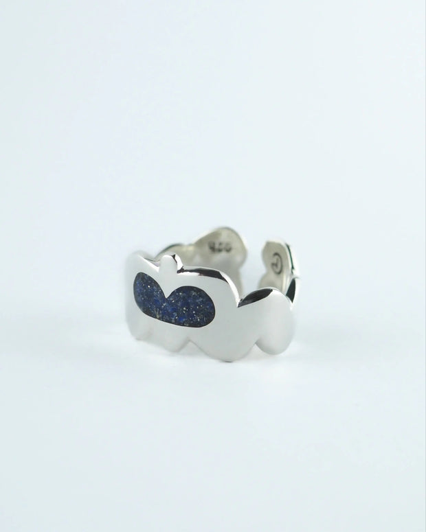 Anillo plateado con dos piedras ovaladas azules y detalle en el lateral