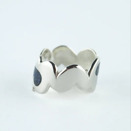 Anillo ancho plateado con piedras azules oscuras y bordes ondulados