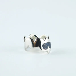 Anillo plateado con piedras azules en forma de gota sobre banda ondulada