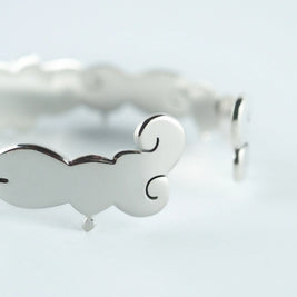 Pulsera plateada con detalles calados en forma de corazón, acabado brillante.