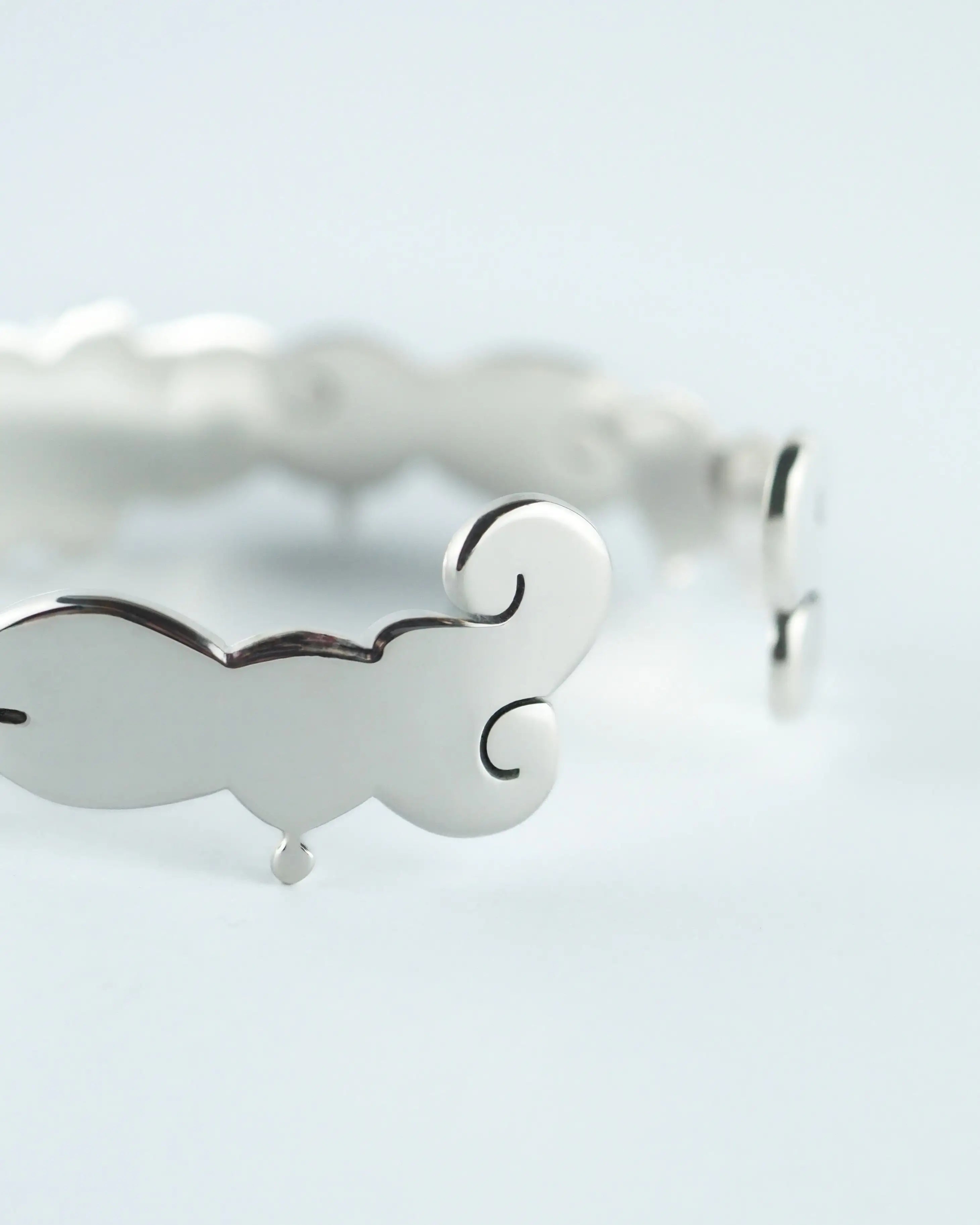 Pulsera plateada con detalles calados en forma de corazón, acabado brillante.