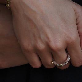 Anillo Opuntia en la mano, banda plateada con cuentas doradas y acabado brillante