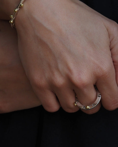 Anillo Opuntia en la mano, banda plateada con cuentas doradas y acabado brillante