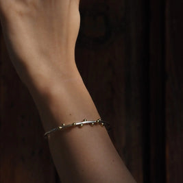 Pulsera Opuntia en la muñeca, brazalete plateado con cuentas doradas pequeñas
