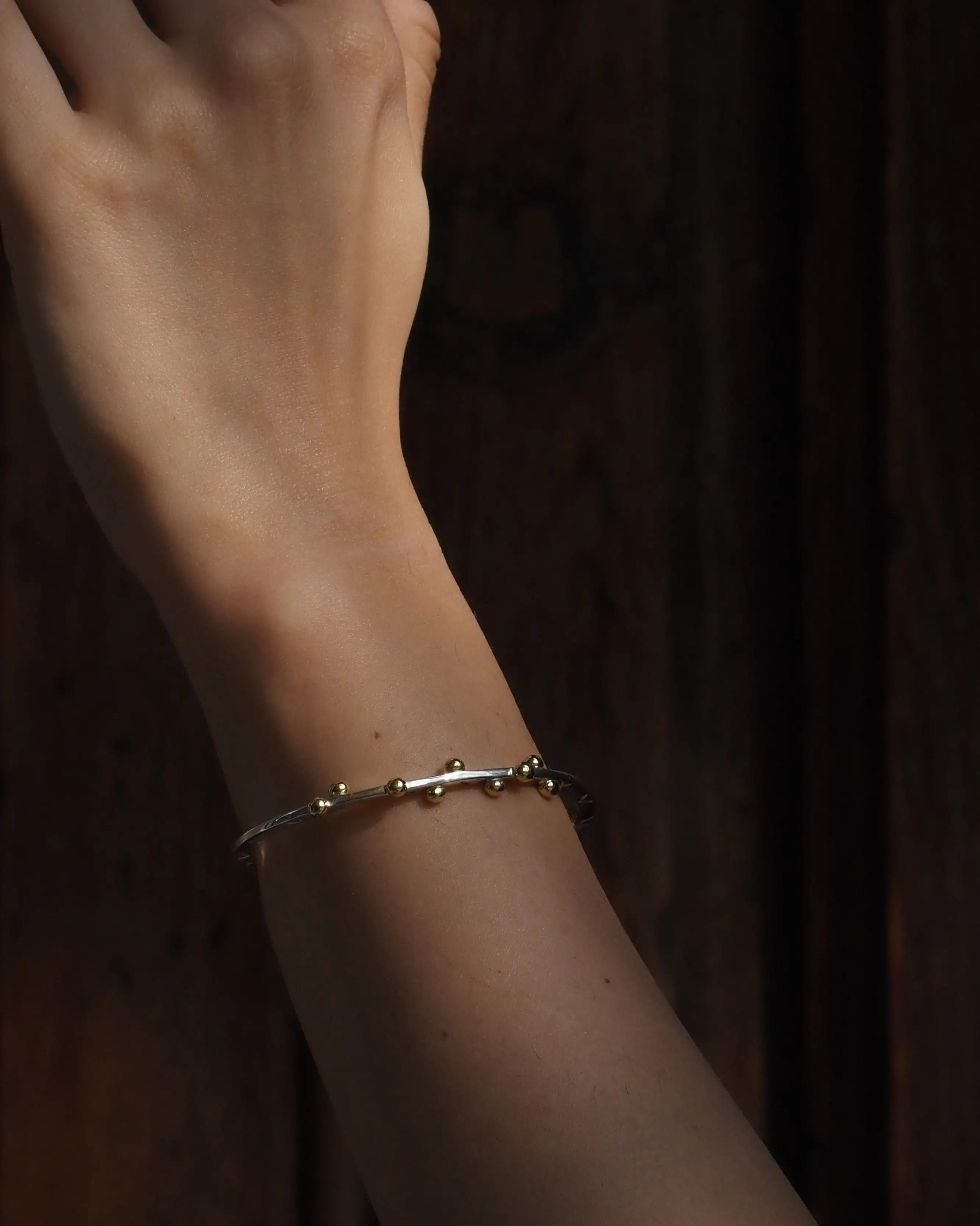 Pulsera Opuntia en la muñeca, brazalete plateado con cuentas doradas pequeñas