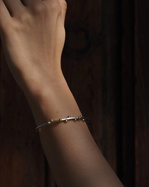 Pulsera Opuntia en la muñeca, brazalete plateado con cuentas doradas pequeñas